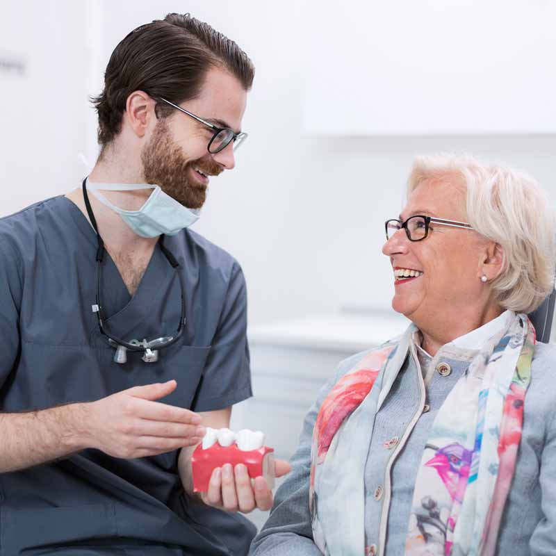 Dr. Gert Jungbauer MSc. im Gespräch mit einer älteren Patientin – vertrauensvolle und einfühlsame Zahnmedizin für alle Generationen in Straubing